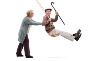 Elderly woman pushing a man on swing